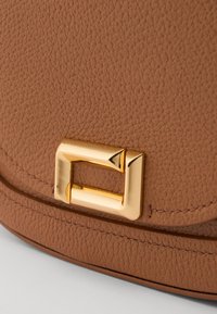 Bolsa de mão de couro castanho com acabamento texturizado, um fecho em metal dourado destacado e costura curva ao longo das bordas.