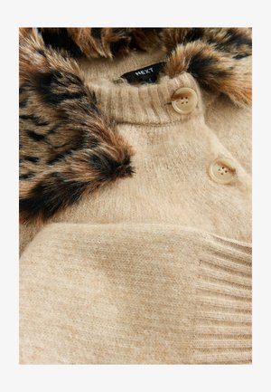 Beige stickad tröja med en leopardmönstrad pälskrage, prydd med två runda knappar och ett texturerat, ribbat mönster längs fållen.