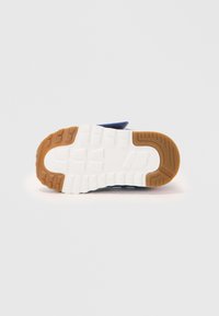 Semelle de chaussure de sport bleue avec un intercalair blanc texturé et une semelle extérieure en caoutchouc brun. Présente un motif de adhérence surélevé pour plus de traction.