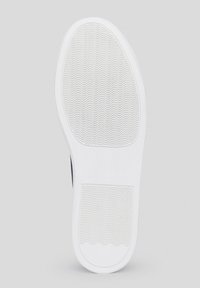 Biała gumowa podeszwa buta z falistym wzorem bieżnika. Lekko teksturowana powierzchnia z zaokrąglonymi krawędziami i wyraźną częścią pięty. Prosty, funkcjonalny design.