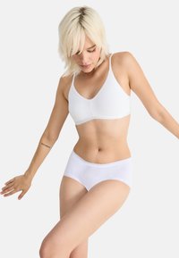 Bralette bianco in cotone con spalline regolabili, abbinato a boyshorts bianchi rifiniti con pizzo. Texture morbida con un design semplice.