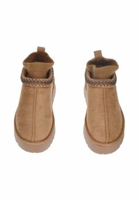 Stivaletti ankle in suede color sabbia con risvolto lavorato a punto, cuciture decorative intorno al colletto e suole in gomma testurizzata.