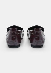 Burgundia nahast loafers krokodillimustriga, lamelaud ja mustad aktsendid krae ääres. Tagantvaates on nähtavad õmbluse detailid.