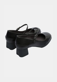 Black leather Mary Jane-style shoes with a rounded toe, flat block heel, and adjustable strap with a buckle detail. Smooth texture.