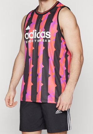 Homme portant un débardeur de sport Adidas sans manches avec des rayures verticales noires, roses et violettes, et un short Adidas noir avec des rayures blanches.
