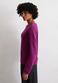 Fuchsia Strickpullover mit langen Ärmeln und Rundhalsausschnitt, der ein strukturiertes Muster und eine lockere Passform aufweist.