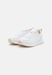 Scarpe da ginnastica bianche con tomaia in pelle liscia, accenti beige e suola in gomma testurizzata. Presentano lacci piatti e un piccolo tab sul tallone.
