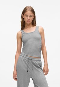 Canottiera grigia con un design aderente, texture a coste e scollo rotondo, abbinata a pantaloni grigi con coulisse dello stesso colore.