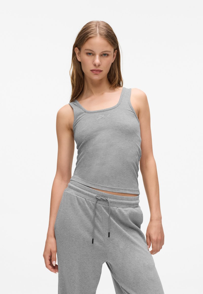 Canottiera grigia con un design aderente, texture a coste e scollo rotondo, abbinata a pantaloni grigi con coulisse dello stesso colore.