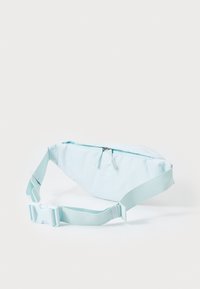 Šviesiai mėlyna audinio fanny pack su lygiu paviršiumi, užtrauktuko uždarymu ir reguliuojama juosta. Pasižymi paprastu, minimalistiniu dizainu.