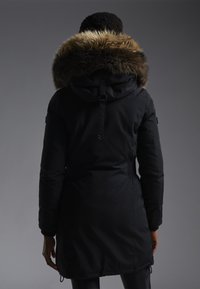 Černá parka s velkým kapucí lemovaným kožešinou, stahovacími pasem a elastickými manžetami. Hladká textura, nastavitelné prvky a lehký design.