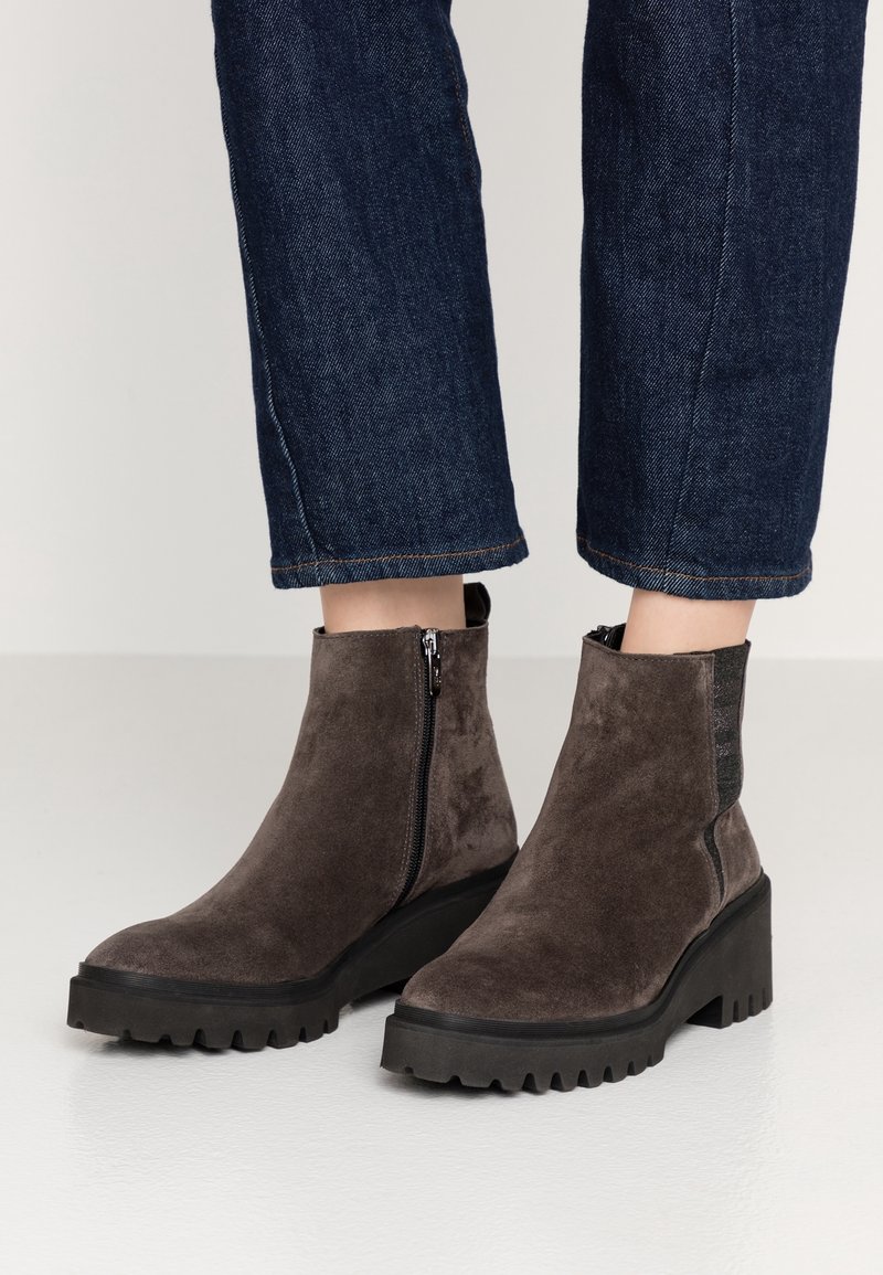 Šedé nubukové kotníkové boty s masivní černou gumovou podrážkou. Obsahují boční zip a texturovanou část na patě. Neformální design s pevnou konstrukcí.