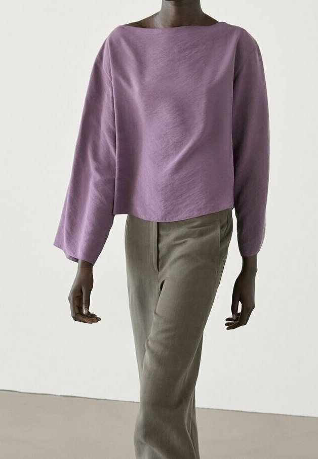 Blouse violette ample et raccourcie avec des manches larges, associée à un pantalon beige taille haute à jambe droite. Texture douce, design minimaliste.