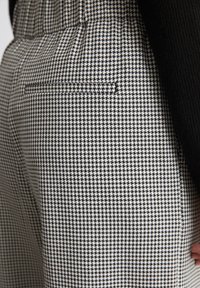 Schwarz-weißes Hahnentrittmuster-Hose mit glatter Textur, ausgestattet mit einer Gesäßtasche und hohem Bund.