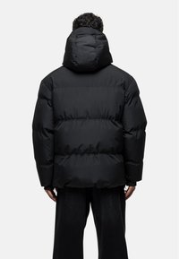 Black puffer jacket with a hood, quilted design, loose fit, and smooth texture. Features prominent seams and a short hem.