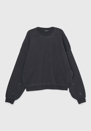 Black sweatshirt with wide sleeves, rounded neckline, and visible stitching. Features snap buttons on cuffs and a relaxed fit design.