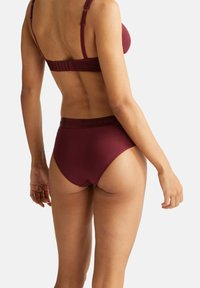 Reggiseno bordeaux e slip a vita alta coordinati, realizzati in materiale morbido e elastico. Il reggiseno presenta spalline regolabili e una chiusura a gancio e occhiello sul retro.