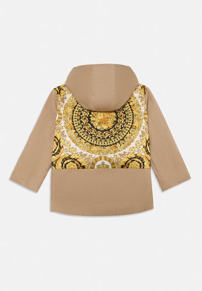 Hiekanvärinen hupullinen takki, jossa yläselässä yksityiskohtainen musta ja kultainen kukallinen barokkikuvio.