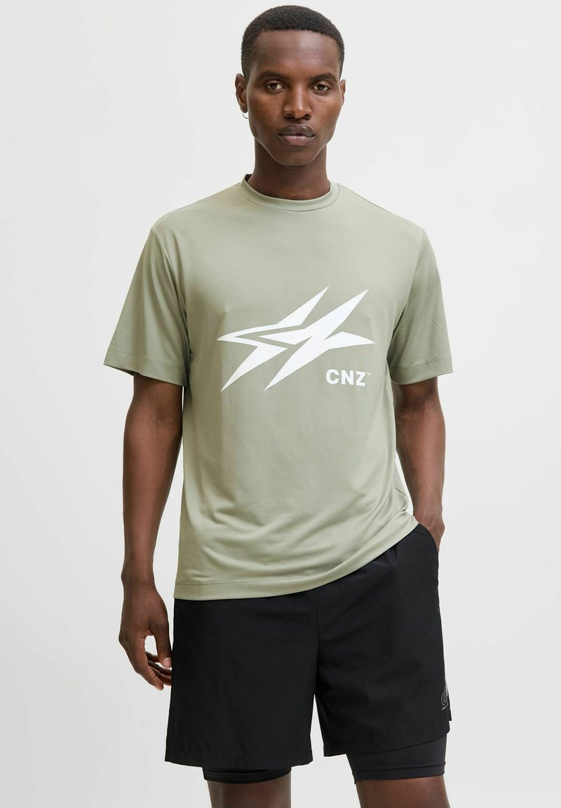 Camisa de manga corta verde oliva con un gráfico blanco de logo 'CNZ' en el frente, combinada con pantalones cortos negros. Textura suave, corte atlético.