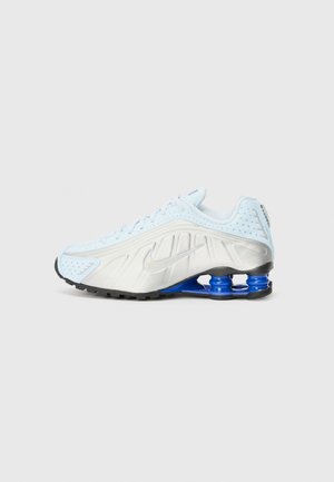 Nike athletic shoe in light blue and silver, featuring a textured upper, perforations, and a blue shock-absorbing heel. Black outsole.