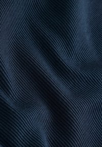 Tissu côtelé bleu foncé avec de fines rayures verticales et de doux plis créant un motif texturé.