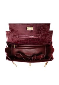 Burgundy läderväska med texturerat krokodilmönster, guldhårdvara och ett inre som har fickor och en dragkedjeavdelning.