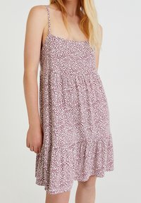 Robe d'été à motif floral en bordeaux et blanc, avec des bretelles spaghetti réglables, un corsage ajusté et un ourlet à volants. Tissu doux au toucher.