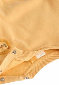 Gul babybodysuit i mjuk bomull med lion broderi och tryckknappar i botten för enkel påklädning.