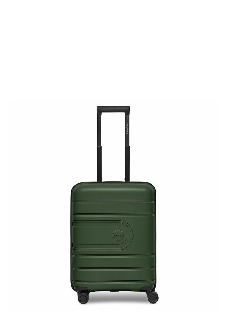 Valigia rigida verde con scanalature orizzontali, manico telescopico nero e quattro ruote per la mobilità. Dettaglio del logo rotondo sulla parte frontale.
