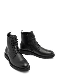 Czarne skórzane botki za kostkę o teksturowanym wykończeniu, z wiązaniem z przodu i zamkiem błyskawicznym z boku. Posiadają okrągły nosek i trwałą gumową podeszwę.