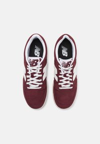 Bordeaux-farbene Wildleder-Sneaker mit weißen Schnürsenkeln und seitlichen Akzenten. Schwarze Innensohle mit Logo. Abgerundete Zehenpartie und gepolsterter Kragen für zusätzlichen Komfort.