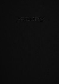Top nero aderente con tessuto testurizzato. Presenta un logo "FREDDY" in rilievo al centro, creando un look elegante e monocromatico.
