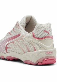 Zapatilla de malla ligera en blanco con detalles en rosa. Presenta una superficie texturizada, un cuello acolchado y una suela acolchada con una tapa de talón rosa.