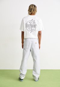 White cropped t-shirt with black "DETROIT" graphic on back, paired with light gray loose-fit cargo pants featuring multiple pockets.