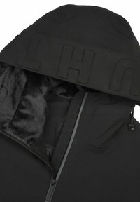 Veste noire à capuche avec doublure en fourrure douce à l’intérieur de la capuche, partiellement zippée, avec des lettres embossées sur le bord de la capuche.
