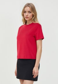 Rode T-shirt met korte mouwen en een ronde halslijn, gemaakt van zachte katoenen stof, met een cropped ontwerp en minimalistische stijl.