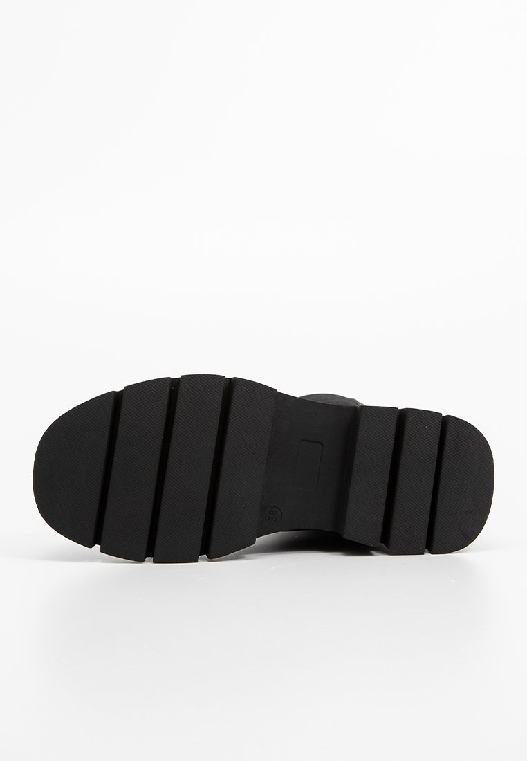 Schwarze Gummisohle mit einem strukturierten Profil, das segmentierte Abschnitte für Griffigkeit und Stabilität aufweist. Numerischer Größenindikator vorhanden.