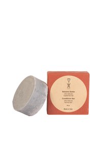 Barra condizionante grigia solida accanto a una scatola rettangolare nei toni terrosi con un'etichetta rotonda. Il testo include "Ultra Delicato" e "Made in Italy."