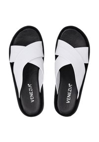 Offene Sandalen mit einem Kreuzriemen-Design aus weißen synthetischen Materialien, einer schwarzen Gummisohle, flachem Profil und strukturiertem Finish.