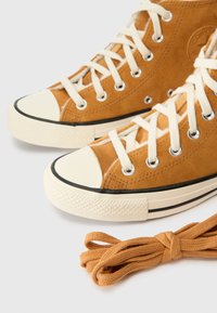 Αθλητικά ψηλά παπούτσια από σουέτ σε ταμπά απόχρωση με λευκά κορδόνια και καουτσούκ σόλες. Διαθέτουν στρογγυλή μύτη και μαύρες λεπτομέρειες. Περιλαμβάνε�ται ένα επιπλέον ζευγάρι πορτοκαλί κορδονιών.