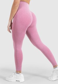 Hochtaillierte rosa Leggings mit einem strukturierten Muster, die eng anliegen und rauchfarbene Akzente aufweisen, kombiniert mit weißen Sportschuhen.
