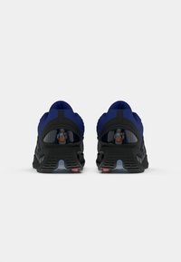 Pair of blue and black athletic shoes viewed from the back with visible Air Max cushioning and textured black soles.