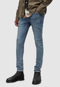 Slim-fit, ljusblå denimjeans med en urtvättad look, med fem fickor, bälteshällor och en lätt förstörd fåll. Matchas med svarta ankelstövlar.