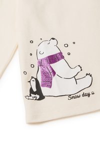 Tessuto color crema con illustrazione di un orso polare e un pinguino. L'orso polare indossa una sciarpa viola glitterata, circondato da fiocchi di neve.
