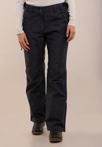 Pantaloni outdoor gri închis cu un finisaj texturat, având două buzunare cu fermoar, o închidere cu buton și o croială lejeră, potrivită pentru mișcare.
