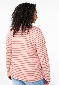 Camicia a maniche lunghe di colore rosa chiaro con strisce orizzontali rosse. Tessuto morbido, scollatura rotonda e vestibilità comoda. Cuciture visibili sulle spalle.