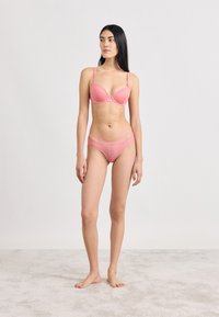 Σετ ροζ δαντελωτής εσωρούχων με στηθόδεσμο επενδεδυμένο, ρυθμιζόμενους ιμάντες και αντίστοιχο μπικίνι με γεωμετρικό σχέδιο.