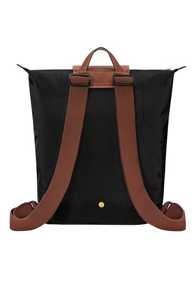 Black fabric backpack with brown leather accents, two adjustable straps, a top handle, and a gold button detail at the base.