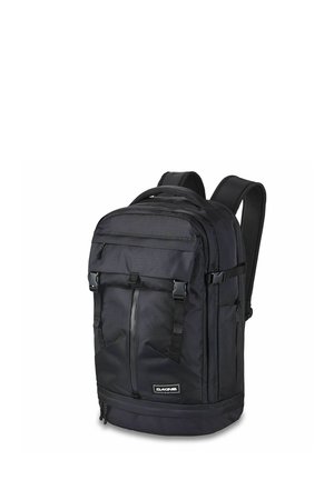 Mochila negra Dakine con múltiples compartimentos con cremallera, correas ajustables y un parche con el logo frontal sobre fondo blanco.