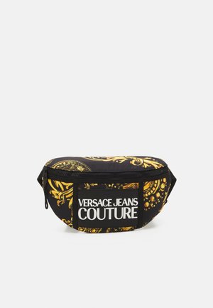 Banane Versace Jeans Couture noire et dorée à motif, avec une poche zippée à l'avant et un logo blanc audacieux sur le panneau avant.